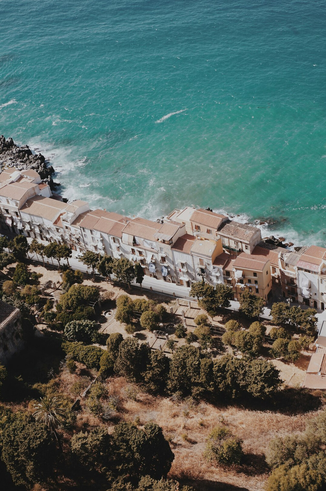 Aerial view of white houses on a cliff above turquoise Mediterranean sea