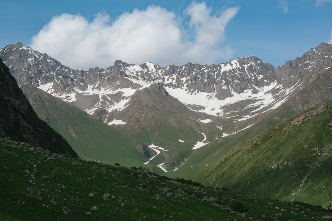 Snow-capped Alpine peaks above green valley