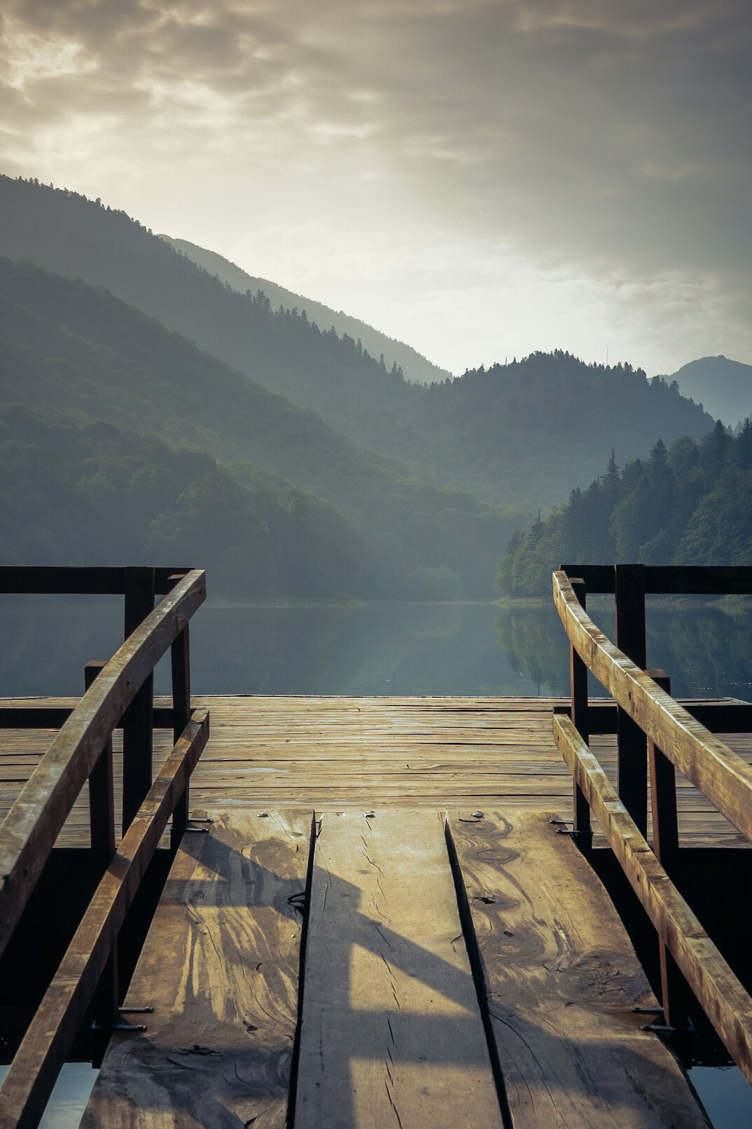 Mountain lake with wooden pier at sunrise
